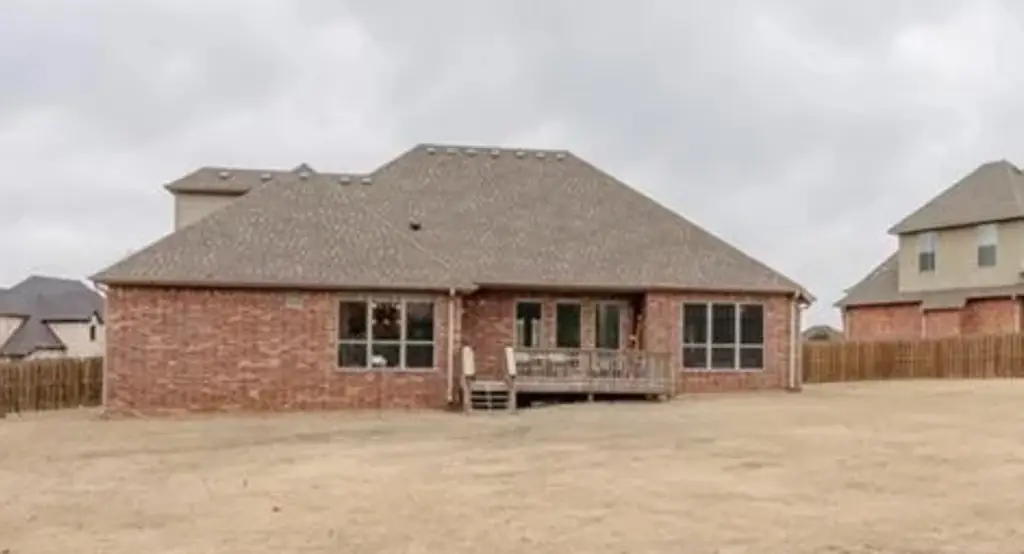The back of a brick home with a finished hip roof
